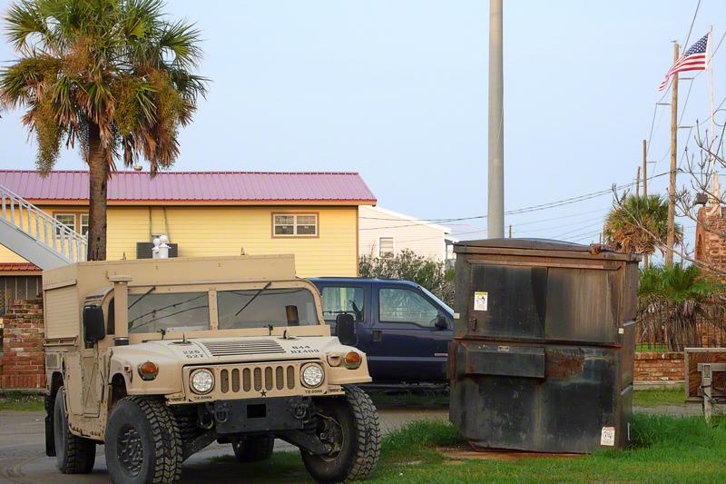 Two military Humvees, one olive green, the other tan,  are parked near the road just yards from our car.